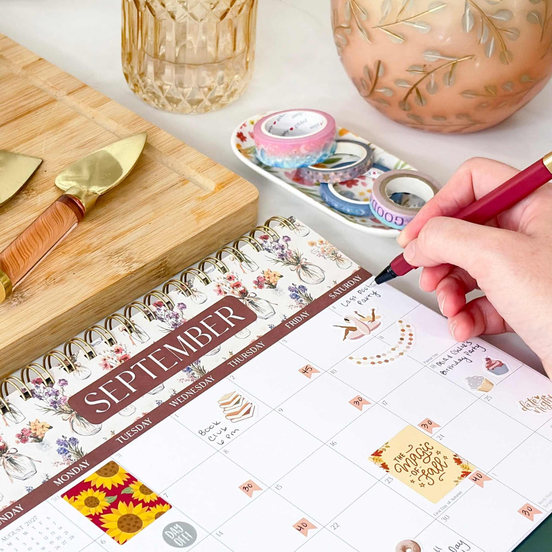 Close up of a hand writing in a September view of a 8 x 10 flip calendar. 