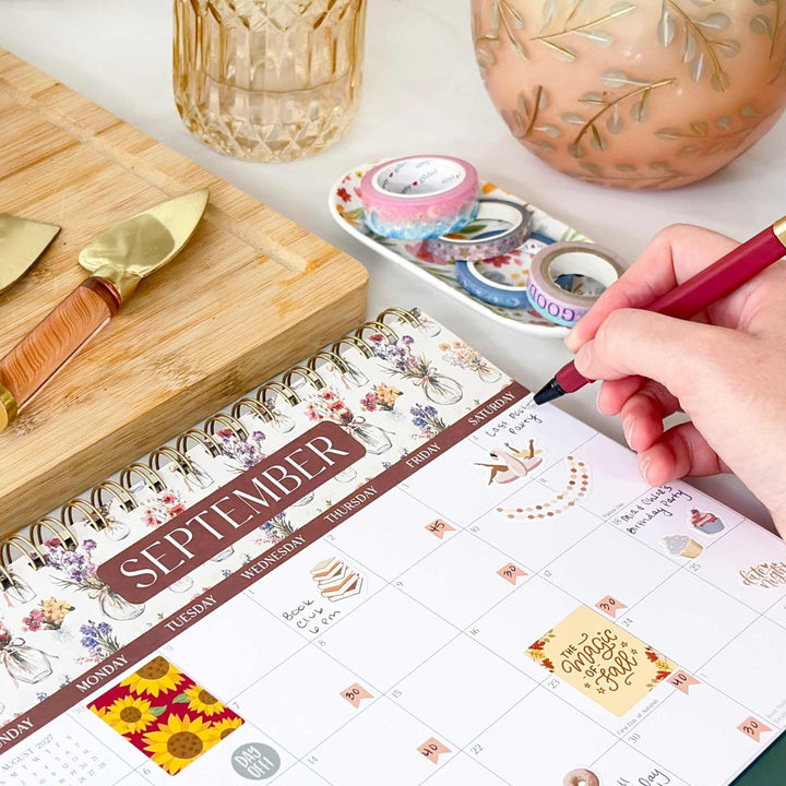 Close up of a hand writing in a September view of a 8 x 10 flip calendar. 