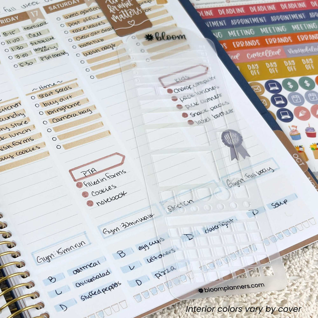 A close-up of a spiral-bound planner page showing a weekly planner layout with handwritten notes, checkboxes, colored headers, and sticker sheets in the background. The brand name bloomplanners.