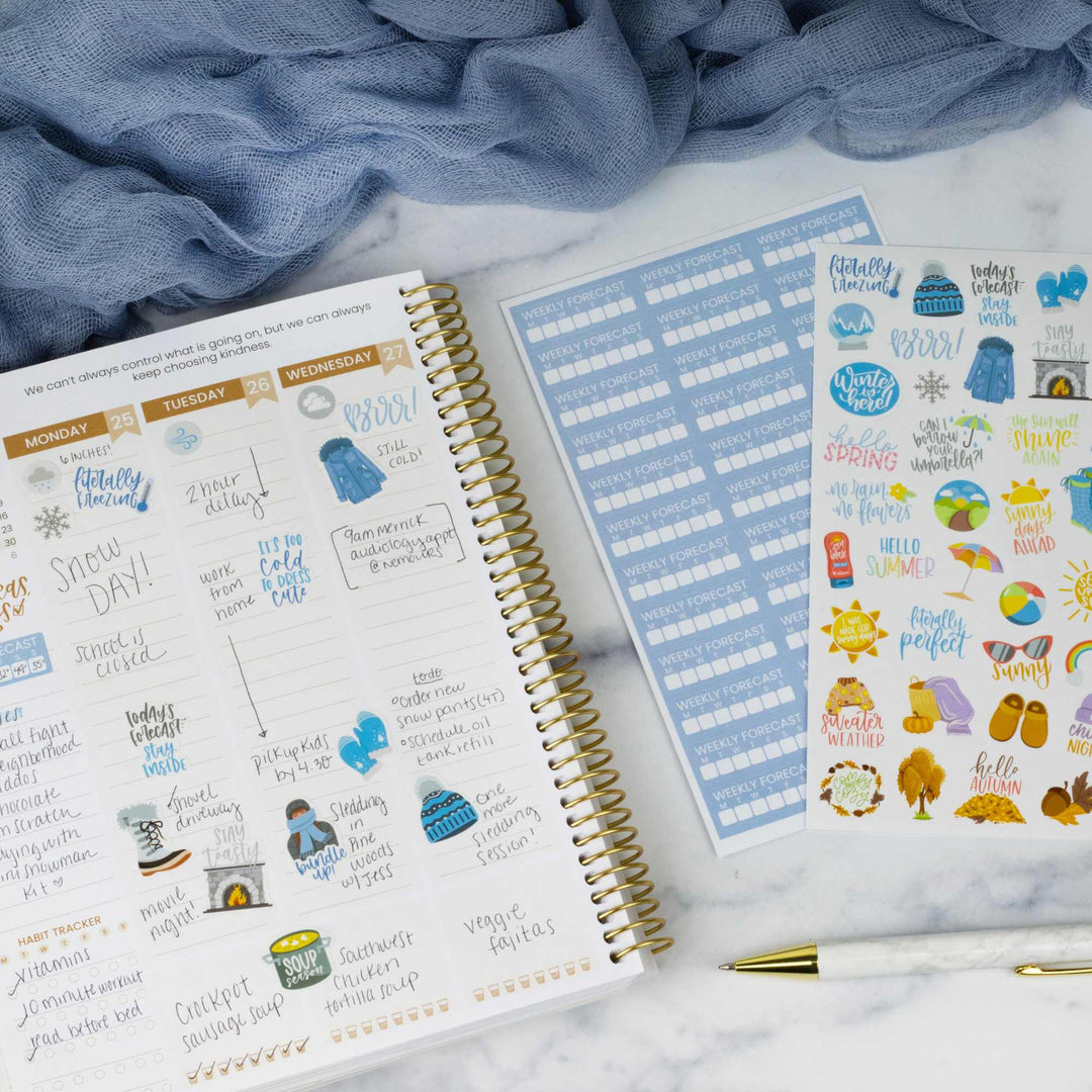 Spiral-bound planner with stickers on a marble surface