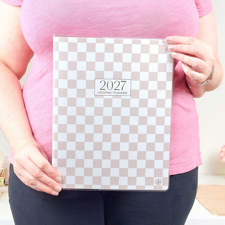 Person holding a 2027 monthly planner with a checkered design