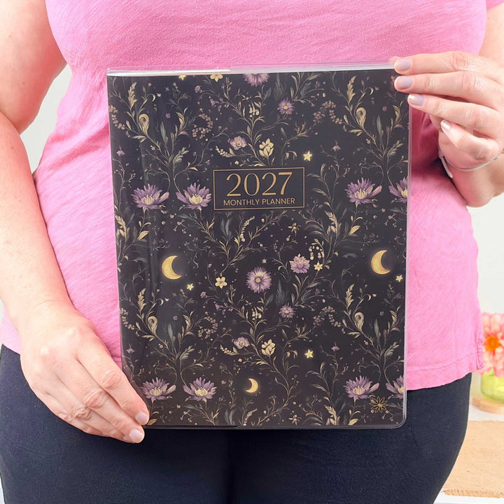Person holding a 2027 monthly planner with floral design