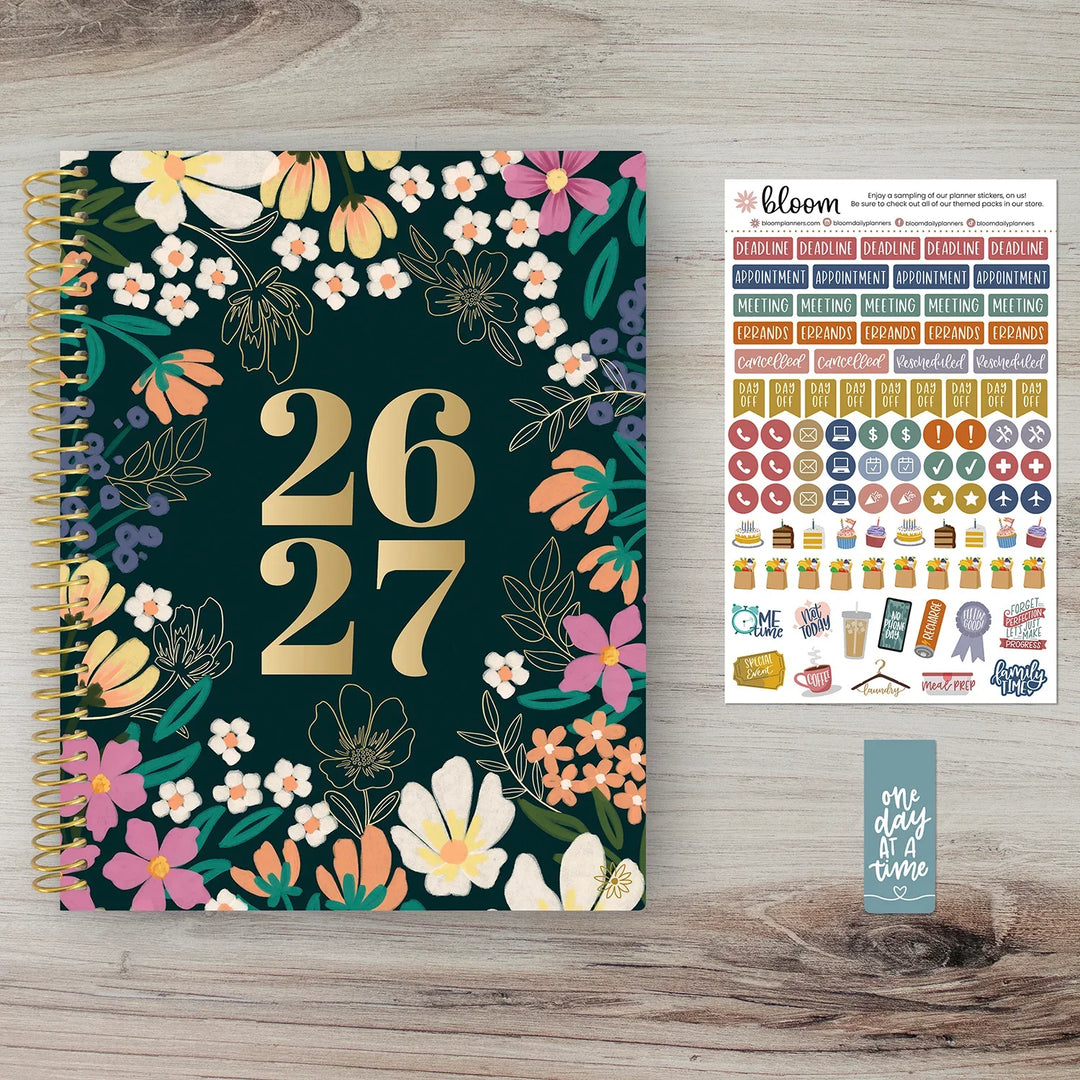 Floral planner with numbers 26 and 27 on a wooden surface, accompanied by a sheet of stickers.