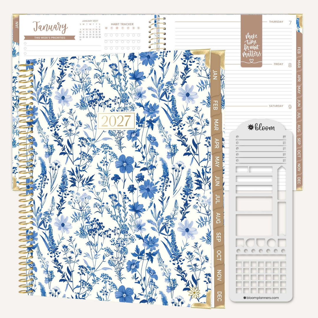 A 2027 spiral-bound planner shown open to a weekly layout page, featuring a blue floral patterned cover, gold-toned spiral binding, beige weekday headers, and a white plastic insert sheet labeled Bloom.
