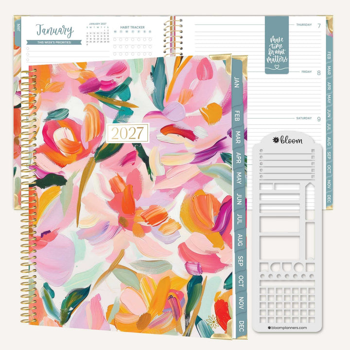 A 2027 spiral-bound planner shown open with floral cover pages, weekly tabs, and a white sticker strip set on a light neutral background. The cover features a colorful abstract floral design in pink, orange, yellow, green, and blue tones.