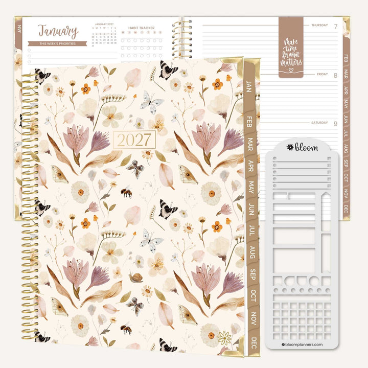 A spiral-bound 2027 planner shown open with floral cover pages, weekly page layouts, and a white sticker sheet on a clean white background. The planner features a cream base with muted pink, beige, and brown botanical illustrations and gold-toned spiral binding.