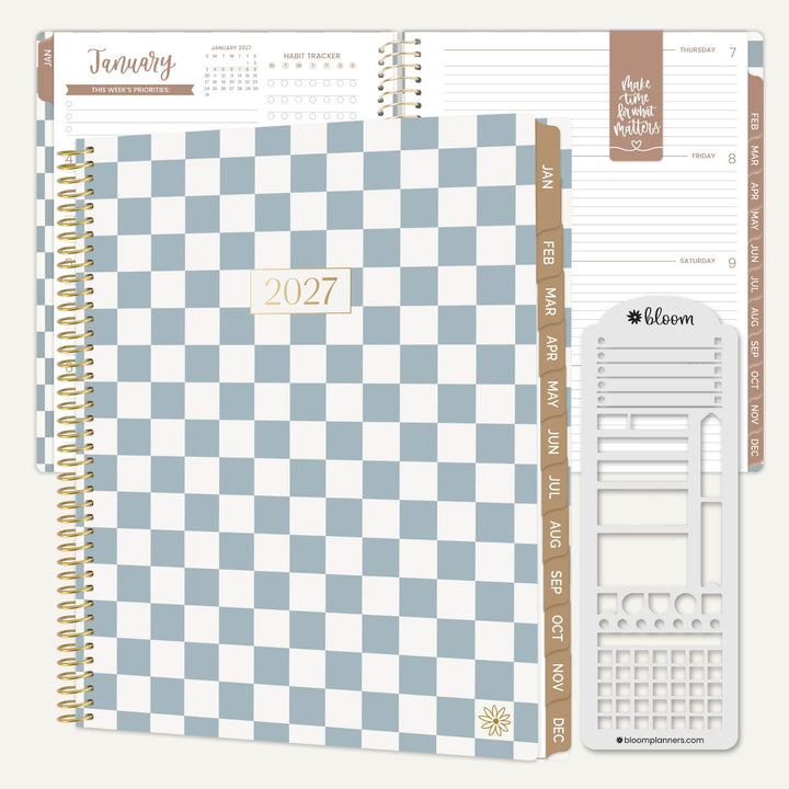 A spiral-bound planner set shown on a light neutral background, featuring a blue-and-white checkerboard cover with gold-toned rings, tan monthly tabs, an open interior page view, and a white plastic insert tool branded bloom.