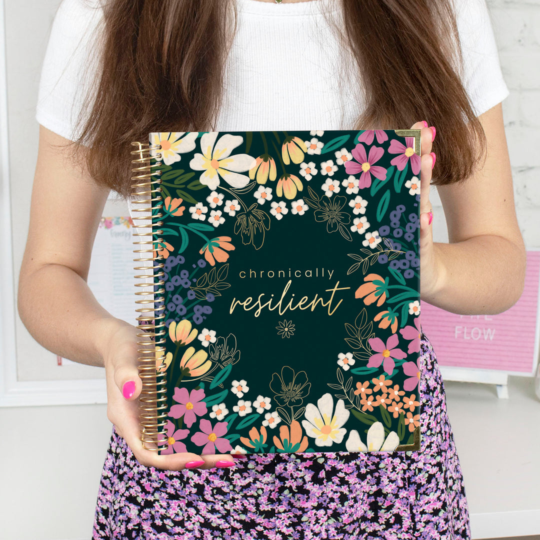 Person holding a notebook with floral design and &