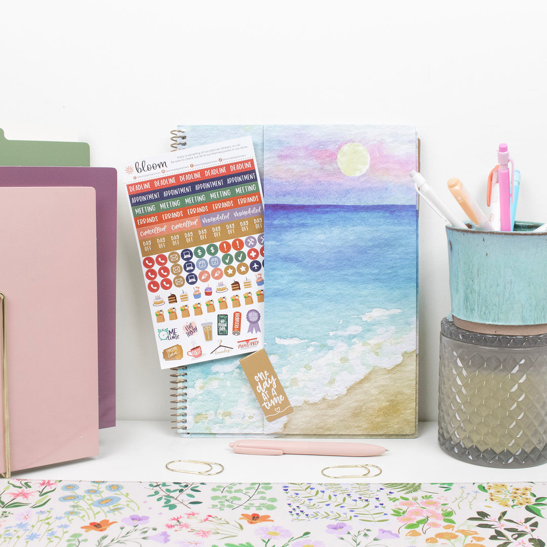 Stationery items including a planner, stickers, and a pen holder on a desk.