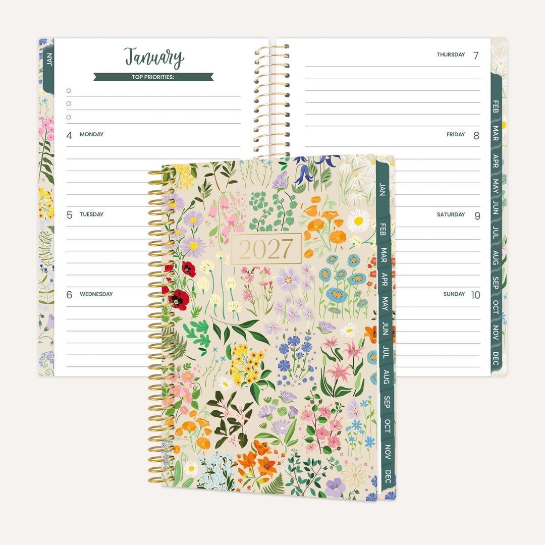 A floral 2027 spiral-bound planner shown open with interior pages visible behind it, plus the closed front cover in front. The cover features a pastel multicolor wildflower pattern with a gold-toned spiral and a cream panel reading 2027.