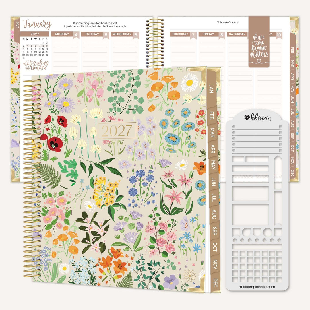 A floral 2027 spiral planner shown open with interior pages and a white sticker sheet, on a clean white background. The cover features a multicolor wildflower pattern on a warm cream base, with gold spiral binding and gold-toned page headers.