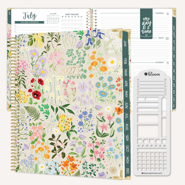 A spiral-bound planner shown open and closed on a light neutral background. The closed cover features a pastel floral print with many flowers and leaves, and the open pages show weekly planning layouts, month tabs, and a white plastic insert sheet.