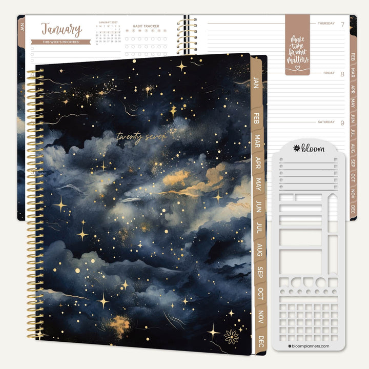 A spiral-bound planner shown open to a navy and black cloudy night-sky cover with gold stars, alongside interior page spreads and a white sticker sheet. The planner has gold wire binding, beige tabbed monthly sections, and visible bloom branding on the sticker sheet.