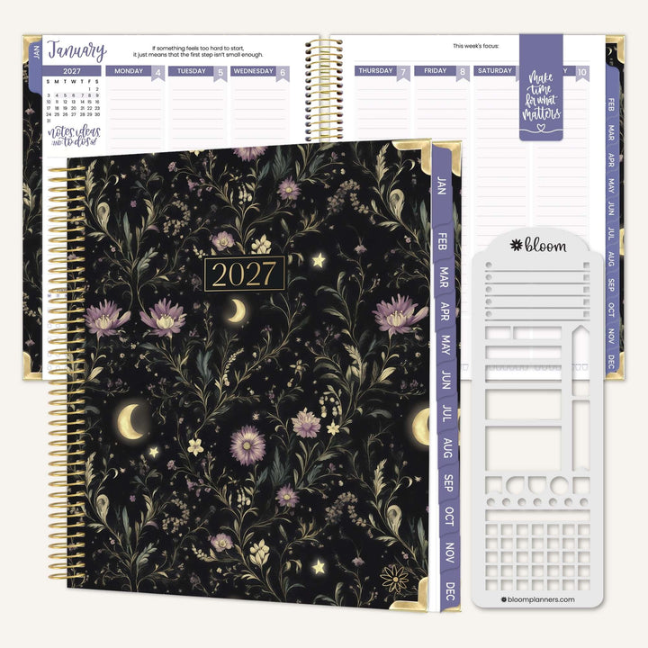 A 2027 spiral-bound planner shown open with floral interior pages and accessories on a light neutral background. The closed cover features a dark floral pattern with gold accents and the year 2027 centered on the front.