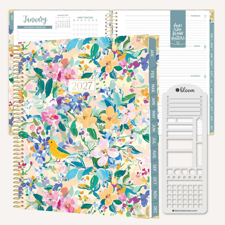 A 2027 spiral-bound planner shown open with floral cover pages, a weekly calendar spread, and a white monthly insert page. The cover features a multicolor watercolor floral pattern with green leaves and a small yellow bird.