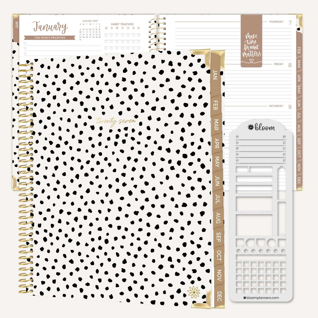 A spiral-bound planner set shown open on a white background, featuring a black-and-white polka dot cover, gold-toned binding and tabs, and white interior pages with planner inserts and a monthly calendar page.