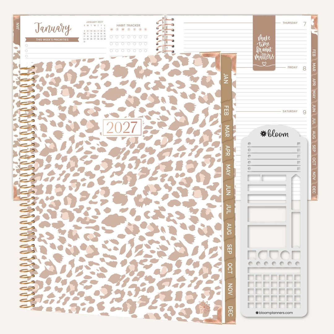 A 2027 spiral-bound planner shown open with interior pages, featuring a leopard print cover in beige and taupe tones, rose-gold-toned ring binder and page accents, and a sheet of white planner stickers on a light neutral background.