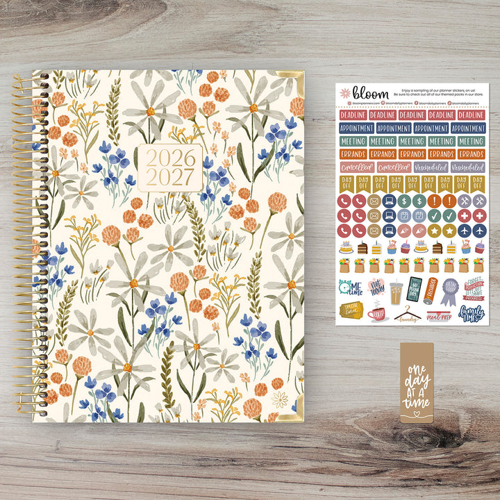 Floral-patterned planner with stickers on a wooden surface
