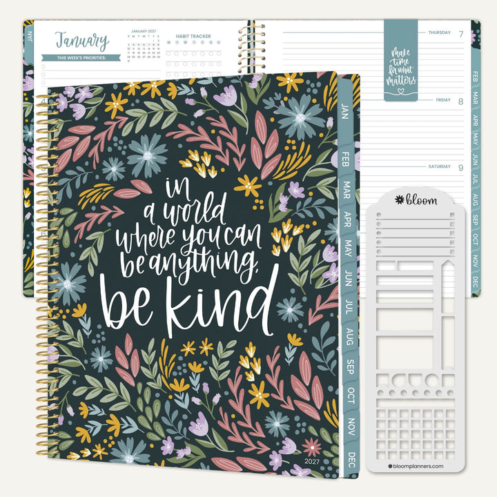 A floral planner shown open to January, with a closed spiral-bound planner in front featuring the phrase “in a world where you can be anything, be kind.” The cover has multicolored flowers and leaves on a dark background.