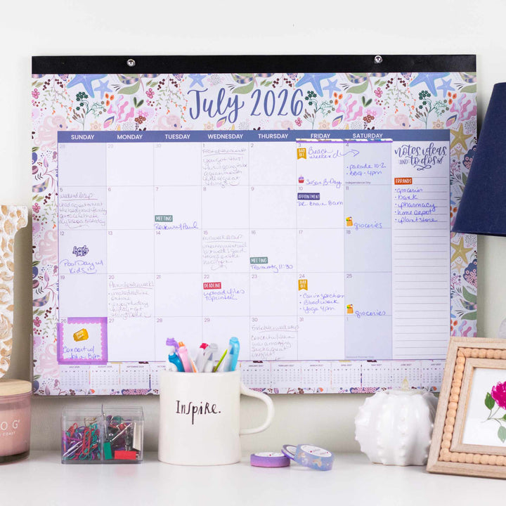 Floral-themed calendar on a wall with office supplies below