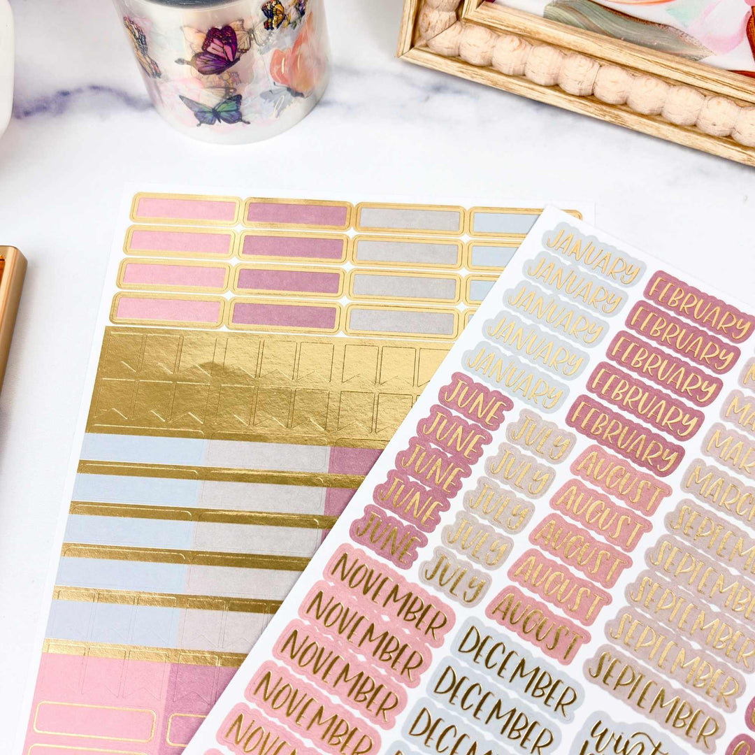 Sticker sheets with gold and pink designs on a white surface