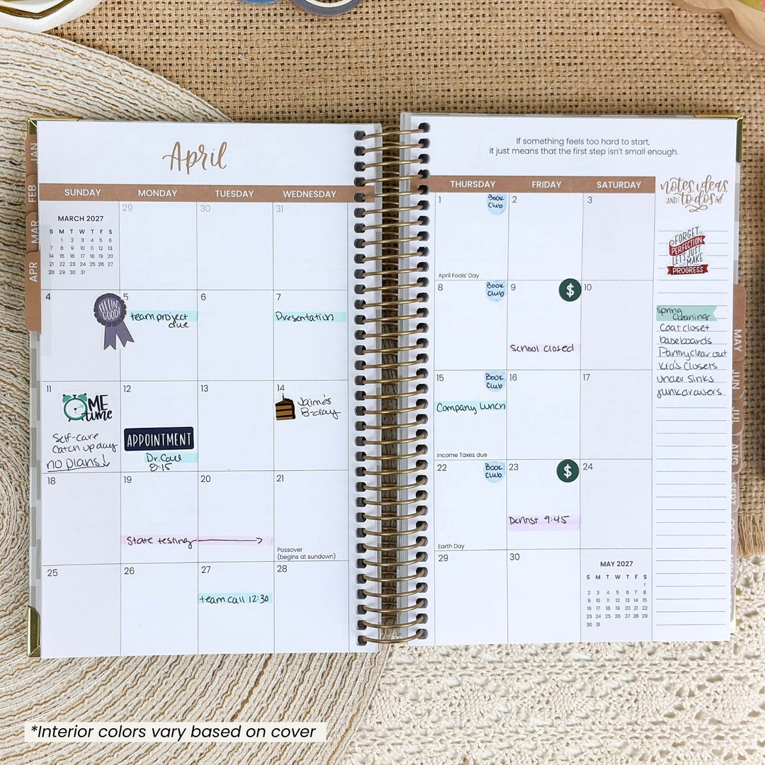 An open spiral-bound planner showing a printed April weekly layout with columns for Sunday through Saturday, decorative header bands, and sample notes. The planner is photographed flat on a beige woven fabric background.