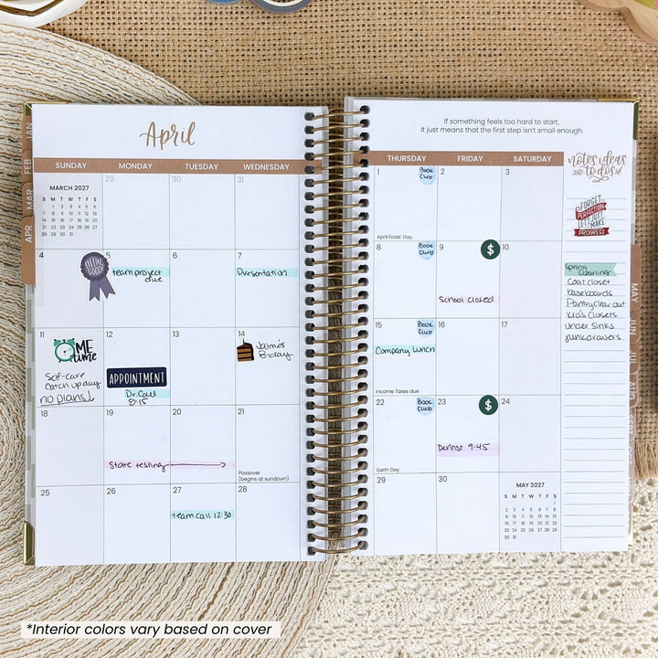 An open spiral-bound planner showing a monthly calendar layout for April with handwritten notes and stickers, placed on a textured beige fabric background.