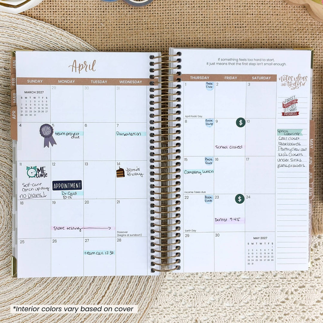 An open spiral-bound planner showing a monthly calendar layout for April with handwritten notes and stickers, placed on a textured beige fabric background.