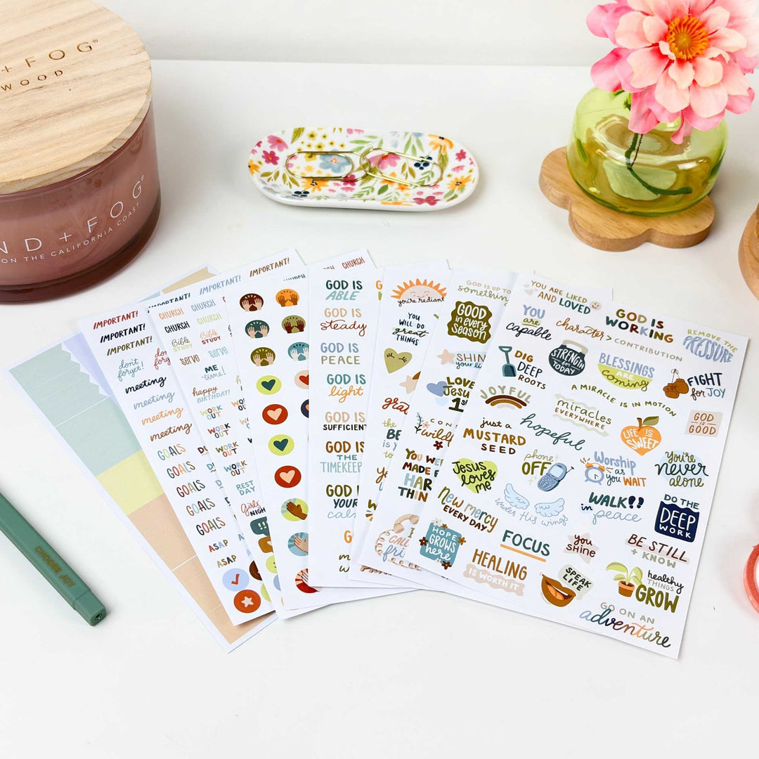 All pages in the pack fanned out on a pretty desk next to a candle and flower vase. 