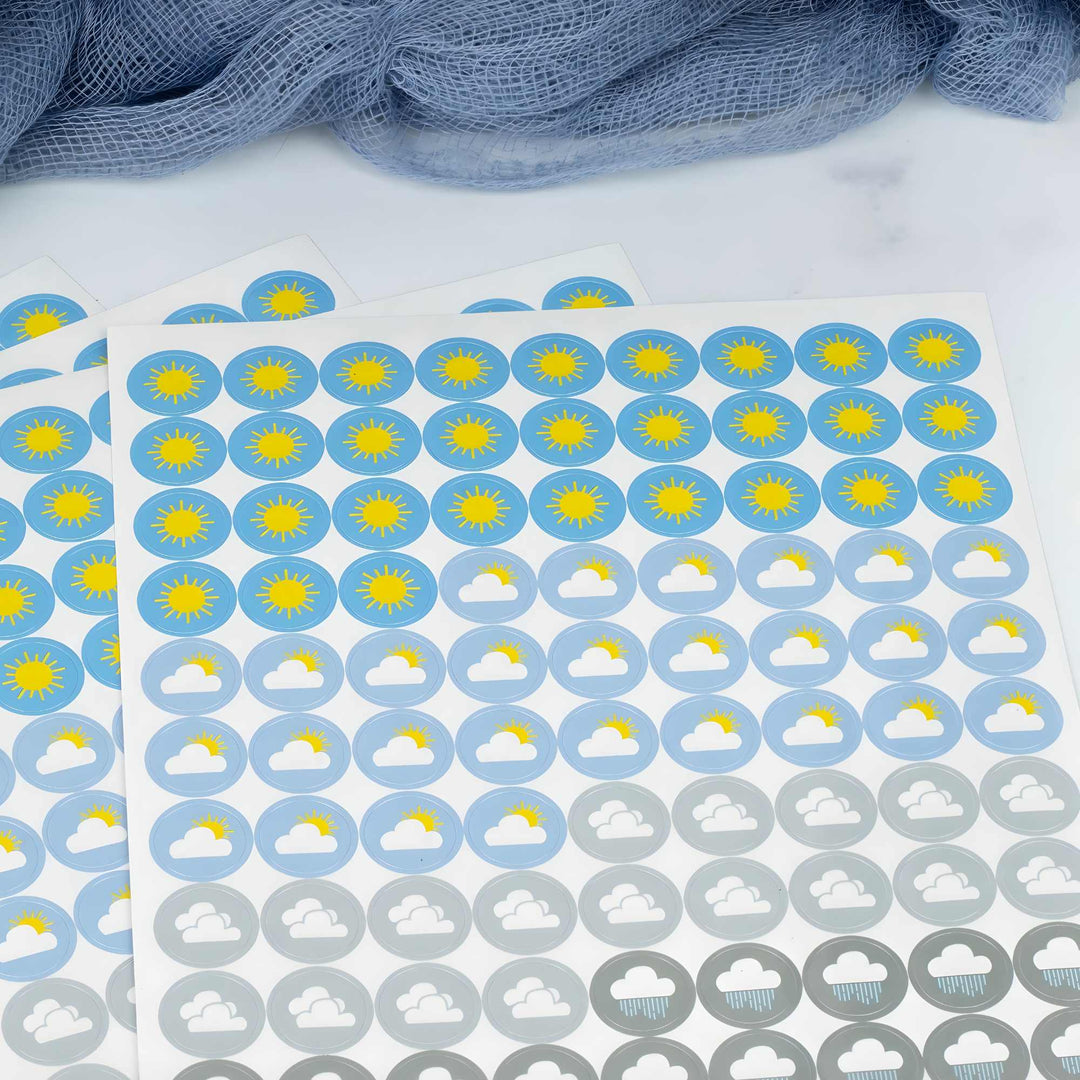 Sheet of weather-themed stickers with sun, cloud, and raindrop symbols on a white background.