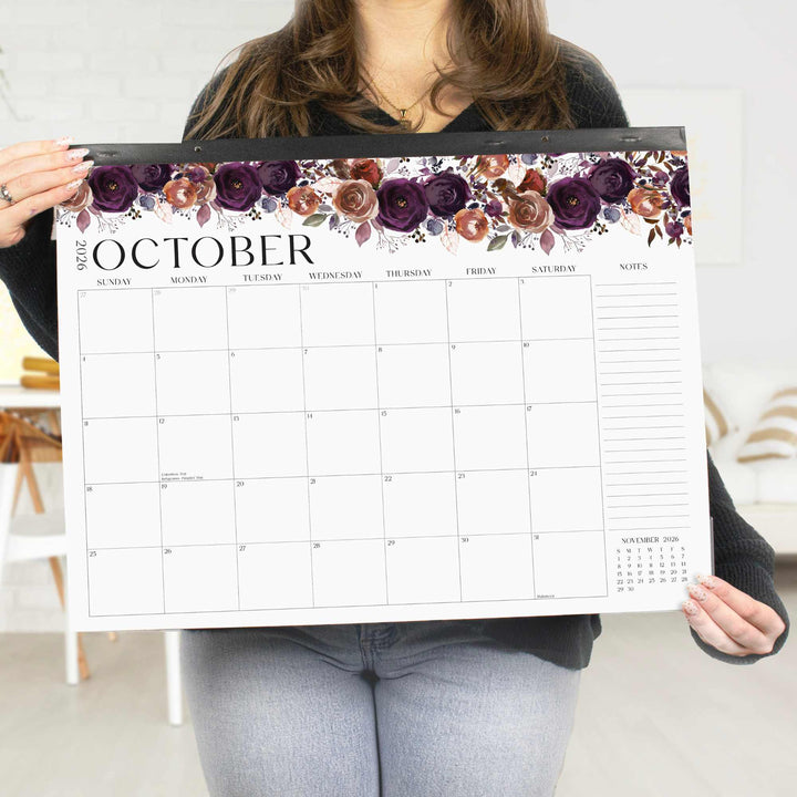 Person holding a large calendar with floral design and 'October' text