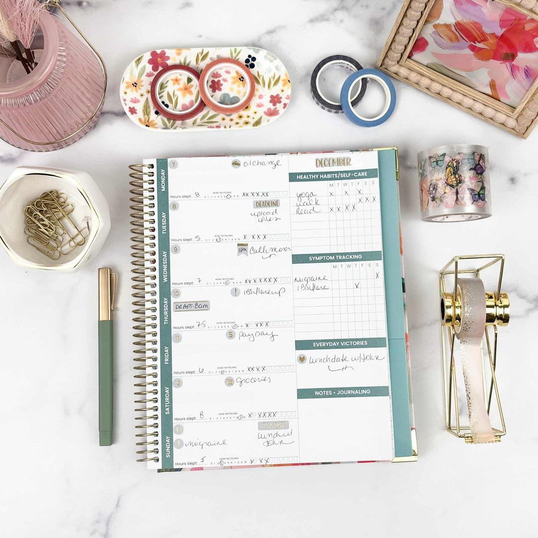 Open planner on a marble surface with stationery items around