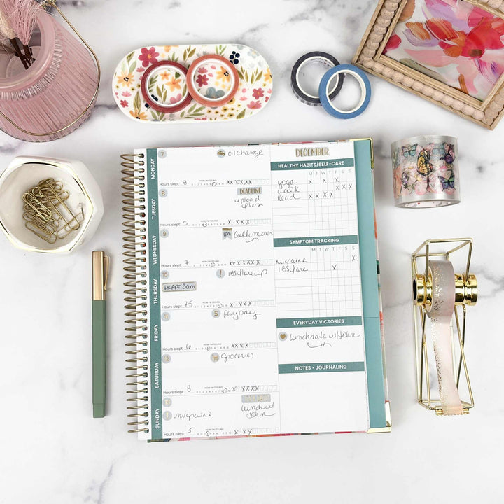 Open planner on a marble surface with stationery items around