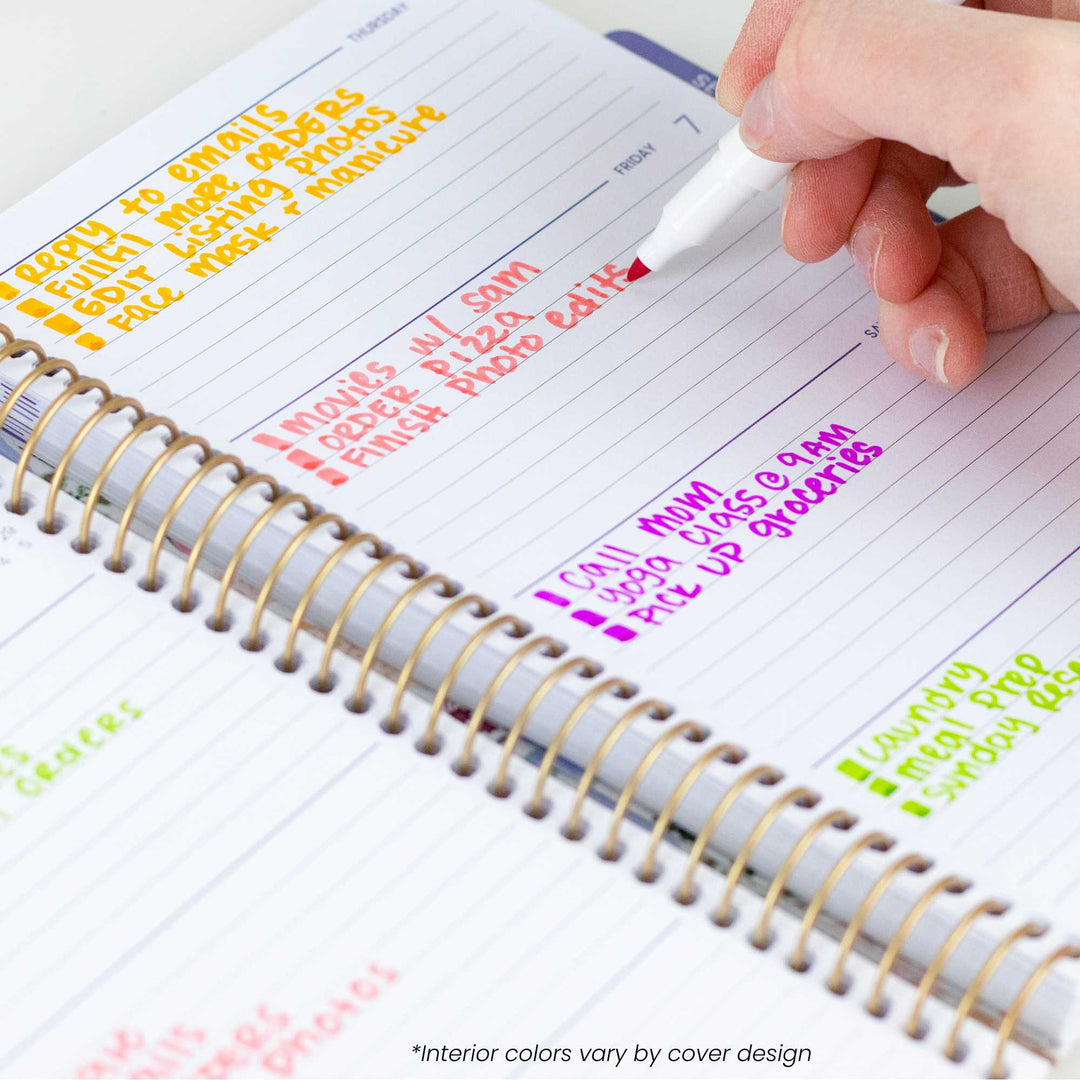 Person using a planner with colorful text and a pen