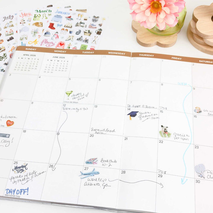 Angled view of May planner with sticker sheets propped behind it