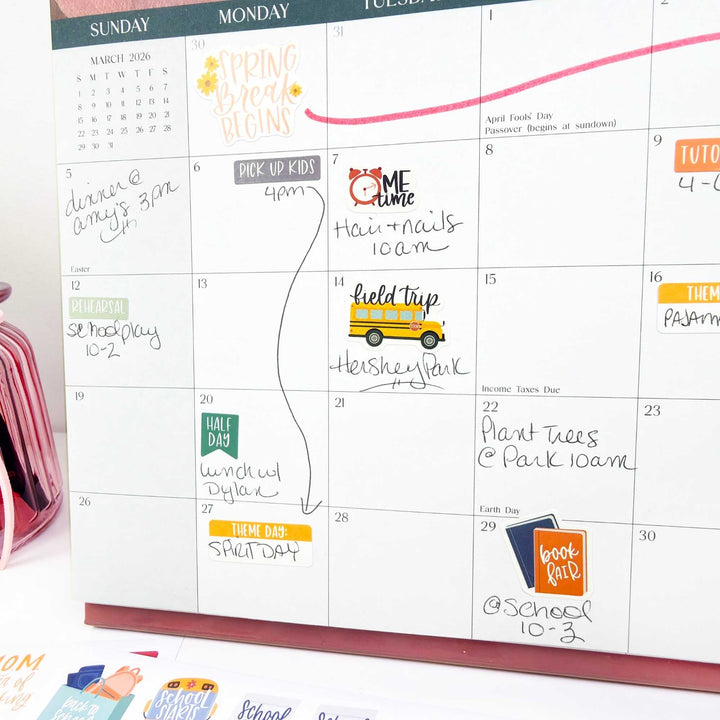 Calendar with hand-written notes and colorful stickers on a white surface