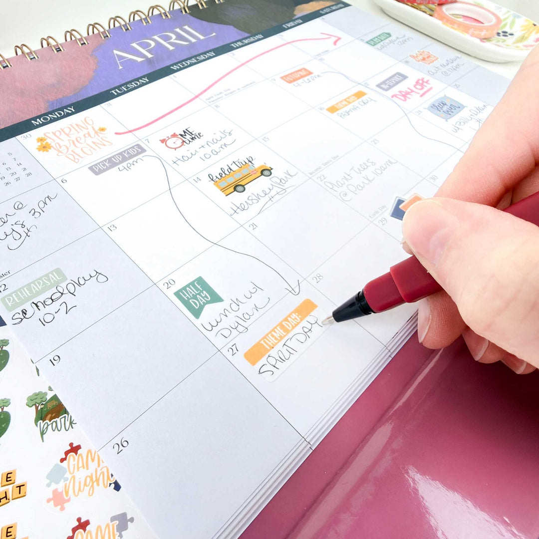 Person marking a date on an April calendar with a red pen