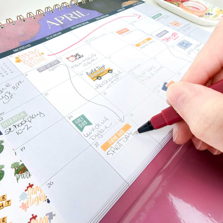 Person marking a date on an April calendar with a red pen