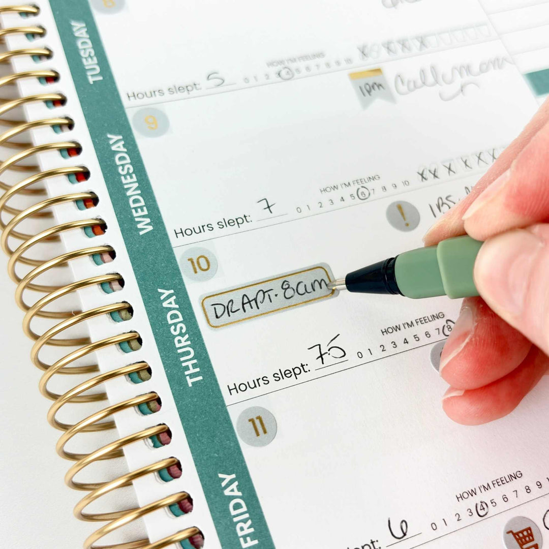 Person writing in a planner with a pen