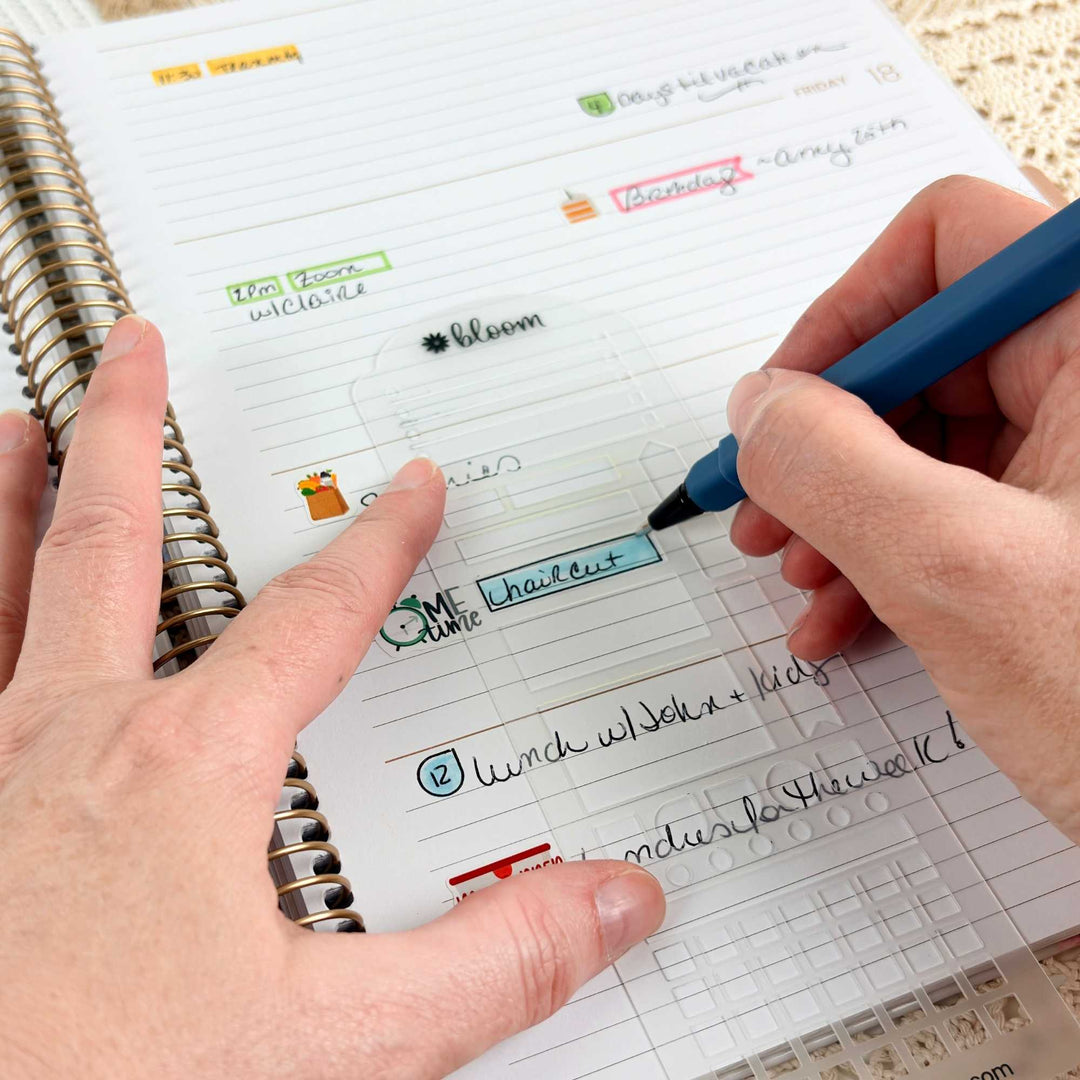 A close-up of a person's hands using a clear plastic planner page protector on a lined spiral notebook, with one hand holding the page in place and the other holding a blue pen to write in a highlighted section.