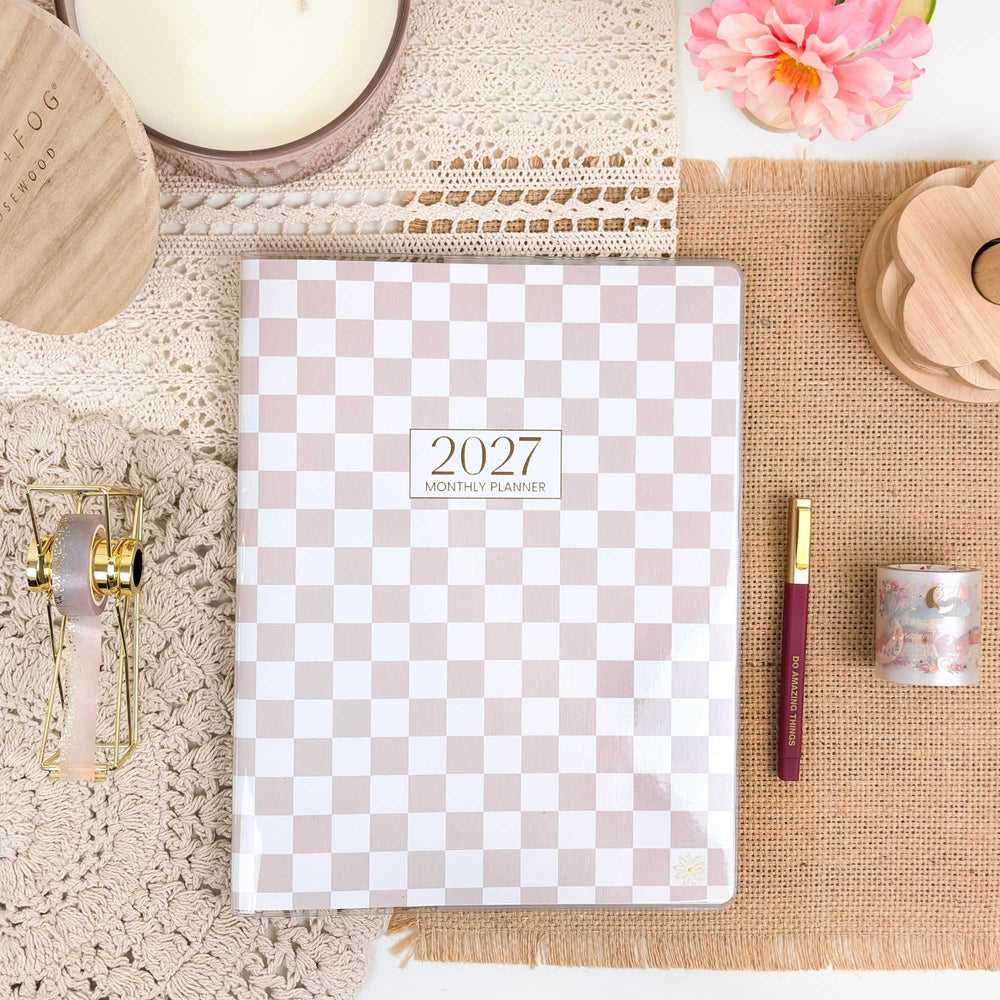 2027 monthly planner with checkered design on a decorative surface with candles and flowers. - hover