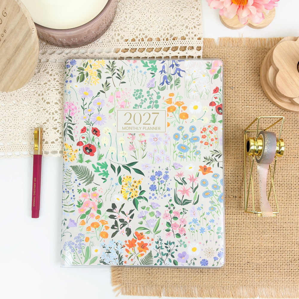 Floral planner with 2027 on a textured surface with decorative items. - hover