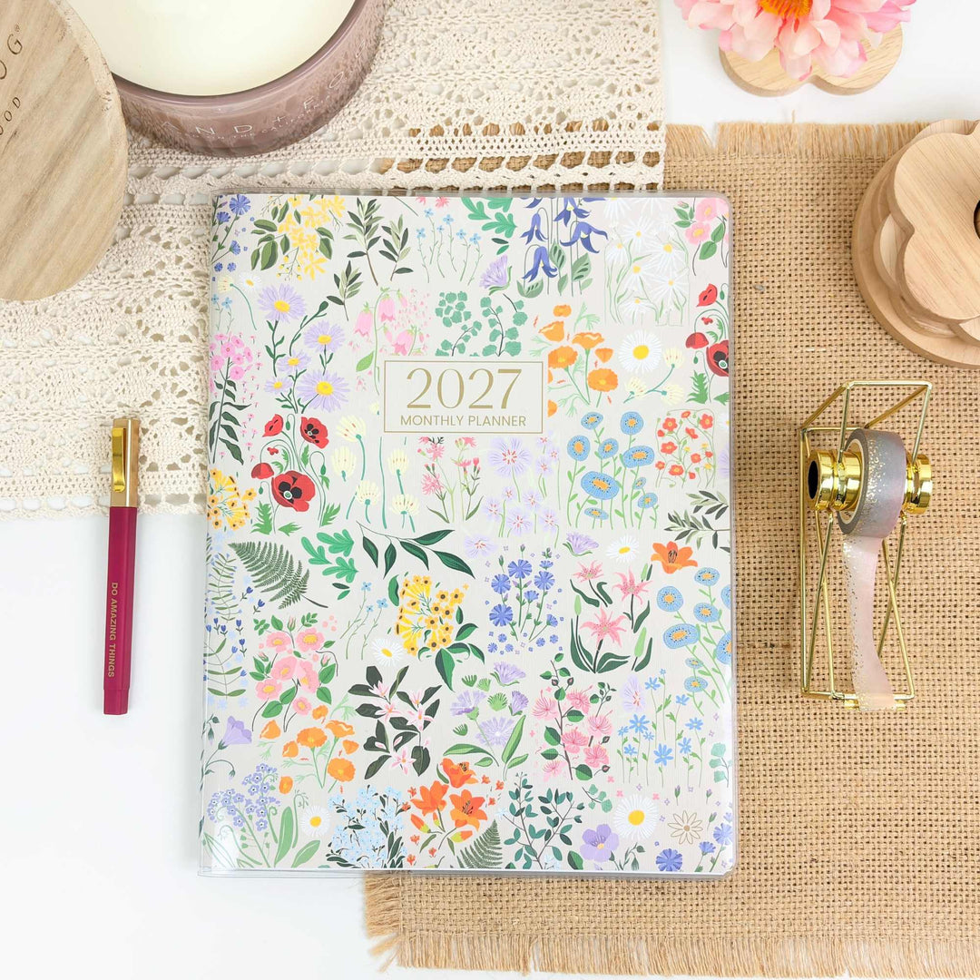 Floral planner with 2027 on a textured surface with decorative items.