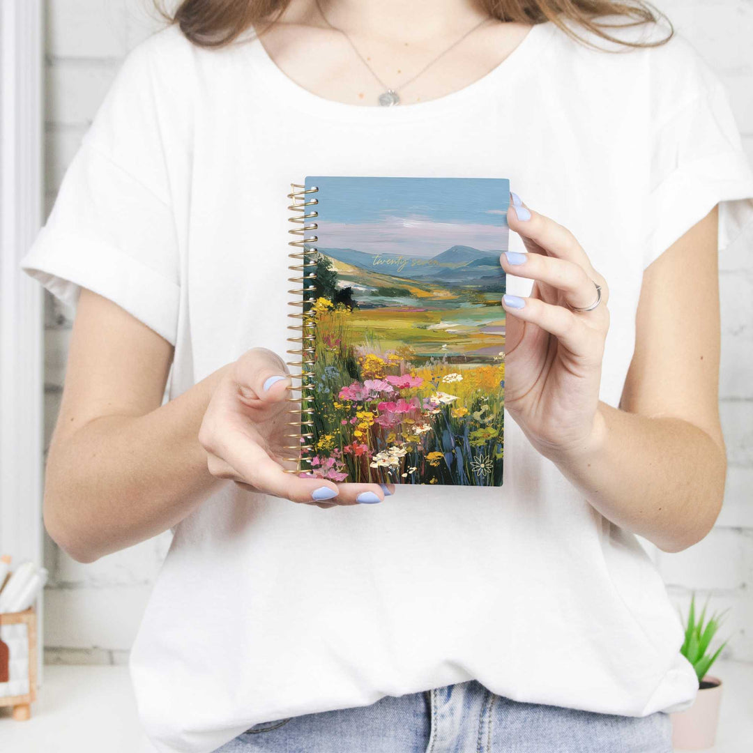 Person holding a notebook with a scenic cover design