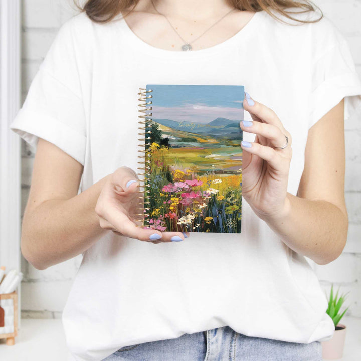 Person holding a notebook with a scenic cover design
