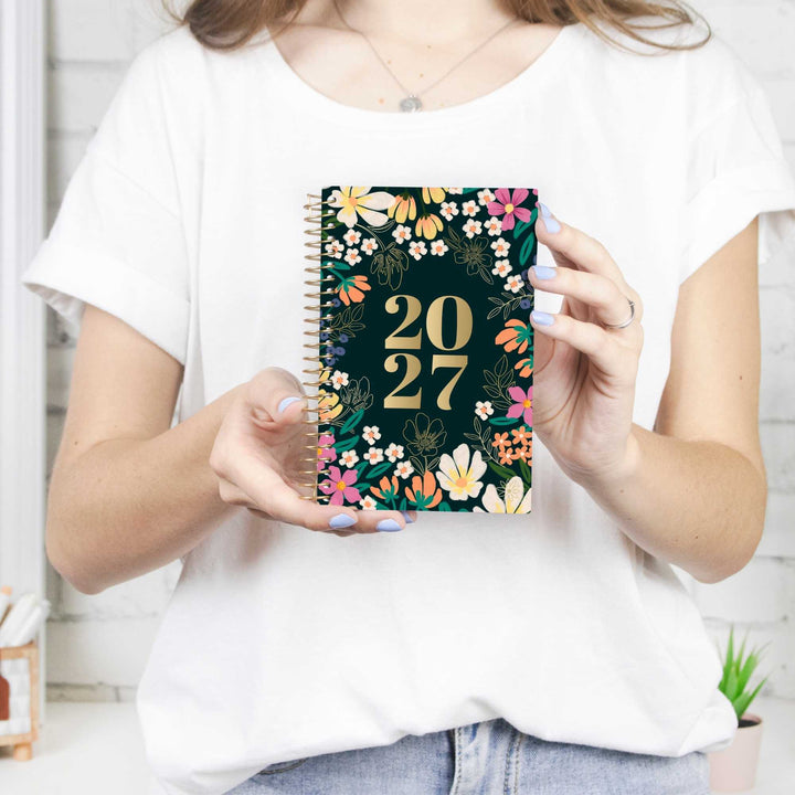 Person holding a 2027 bloom pocket planner with pretty floral accents.