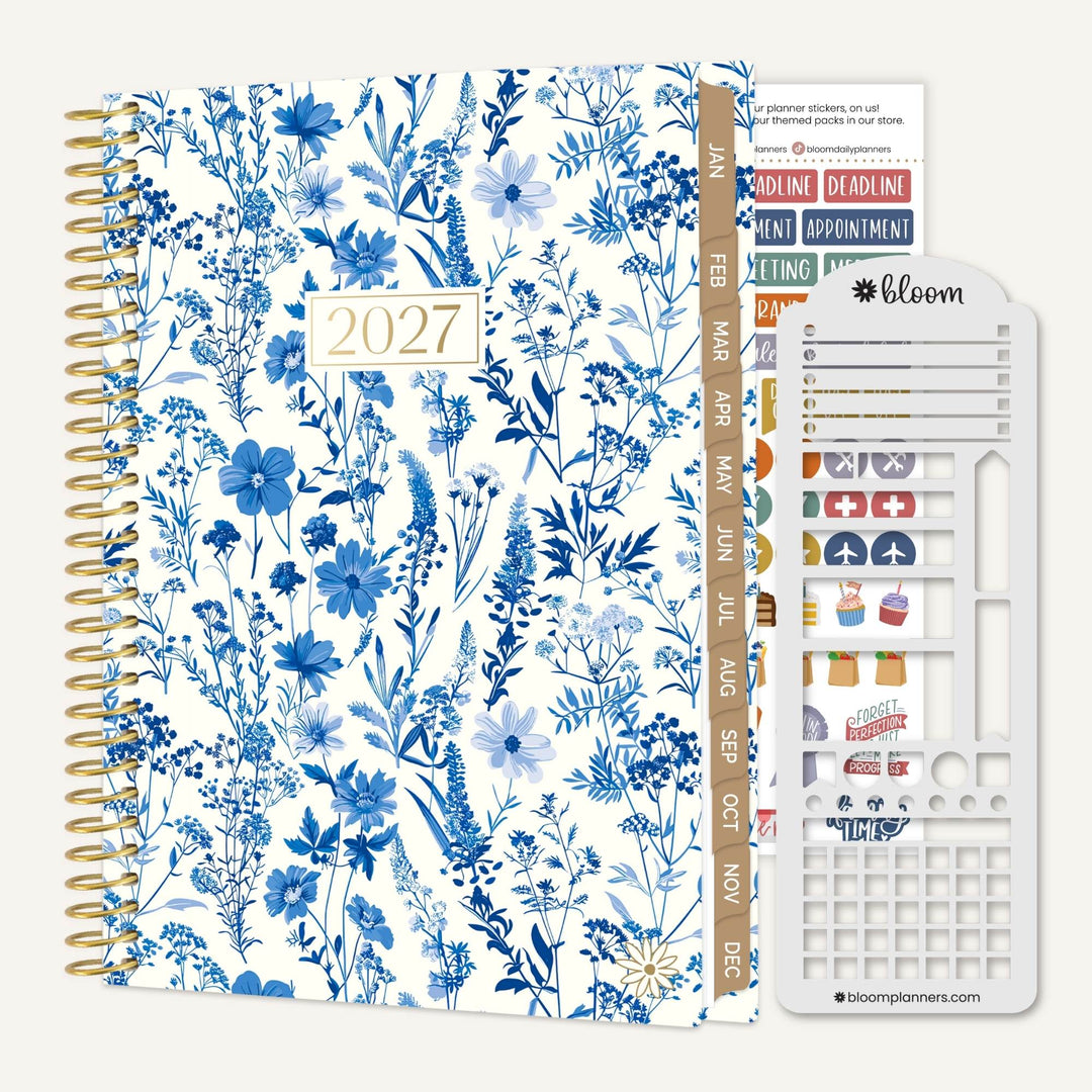 A 2027 spiral-bound planner with a blue and white floral pattern cover, shown with included sticker strips and a white plastic sticker sheet on a light gray background. The brand name 'bloom planners' is visible on the sticker sheet.