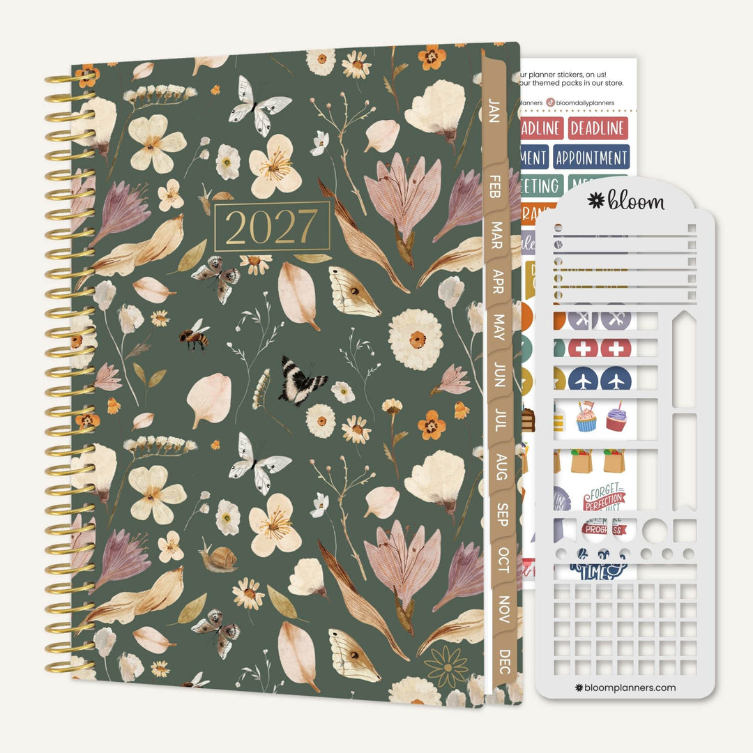 A 2027 spiral-bound planner with a muted green floral and bird patterned cover, shown with a white sticker sheet accessory on a light beige background. The planner cover features a gold-toned spiral binding, a gold '2027' plaque, and a vertical tab with monthly labels.