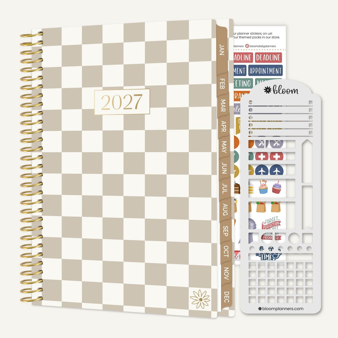 A 2027 spiral-bound planner with a beige and white checkerboard cover, shown alongside a sheet of colorful planner stickers and a white plastic sticker organizer tool on a light gray background.