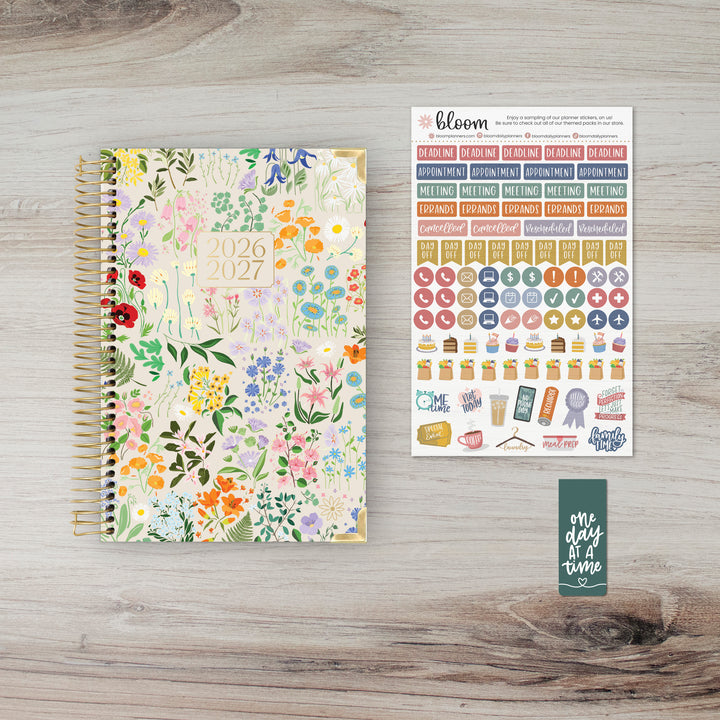 Floral planner with stickers and a bookmark on a wooden surface